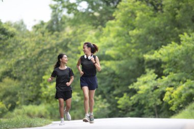 Genç bir kadın ve küçük kız kardeşi sabah egzersizleri için yan yana koşuyorlar, gülüşleri ve senkronize adımları kardeşçe bağlılık ve kararlılığın canlı bir sahnesini yaratıyor..