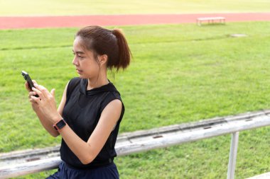 Halk parkında çalışmaya başlamak için can atan genç bir kadın, telefonunda mükemmel müziği arıyor, enerjisini ve motivasyonunu arttıracak ideal çalma listesini bulduğunda yüzü aydınlanıyor..