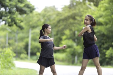 Parkta egzersiz yapmadan önce iki kız kardeş ısınıyor.