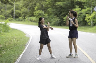 Parkta egzersiz yapmadan önce iki kız kardeş ısınıyor.