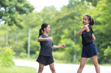 Parkta egzersiz yapmadan önce iki kız kardeş ısınıyor.