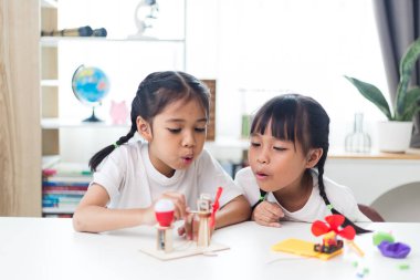 İki kardeş Asyalı kız evde yel değirmeni yığını oynuyorlar.