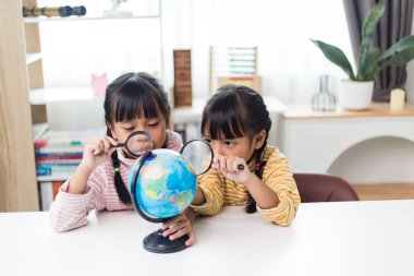 İki kardeş Asyalı evde coğrafya okuyor..