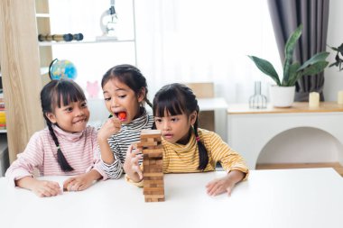 Üç kardeş Asyalı kız evde ahşap destelerle oynuyorlar.