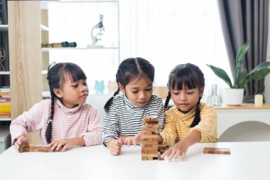 Üç kardeş Asyalı kız evde ahşap destelerle oynuyorlar.