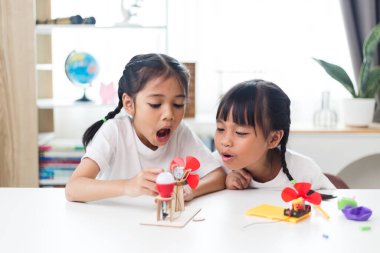 İki kardeş Asyalı kız evde yel değirmeni yığını oynuyorlar.