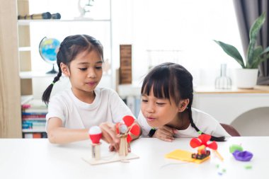 İki kardeş Asyalı kız evde yel değirmeni yığını oynuyorlar.