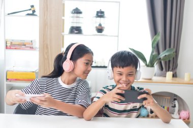 Asyalı çocuklar evde eğlenmek için arkadaşlarıyla çevrimiçi video oyunları oynuyorlar..