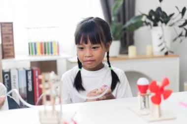 İki Asyalı kız hidrolik güçle çalışan mekanik kavrama çalışmaları üzerinde çalışıyor.