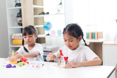 İki kardeş Asyalı kız evde yel değirmeni yığını oynuyorlar.