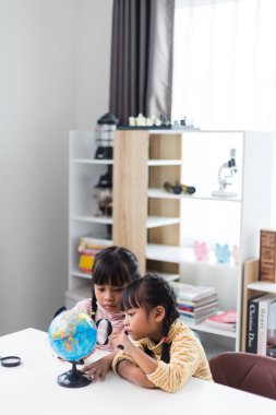 İki kardeş Asyalı evde coğrafya okuyor..