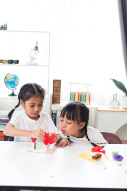 İki kardeş Asyalı kız evde yel değirmeni yığını oynuyorlar.