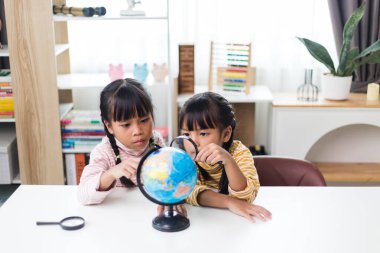 İki kardeş Asyalı evde coğrafya okuyor..