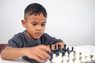 Genç bir çocuk yoğun bir konsantrasyonla satranç oynuyor..