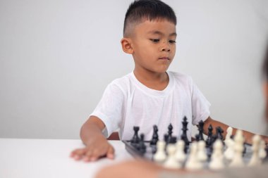 Genç bir çocuk yoğun bir konsantrasyonla satranç oynuyor..