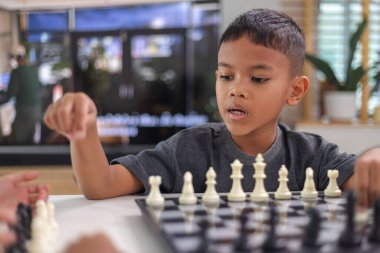 Genç bir çocuk yoğun bir konsantrasyonla satranç oynuyor..