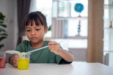 İki genç kız bir masada oturuyor, bir bilim deneyiyle oynuyorlar. Gülümsüyorlar ve eğleniyor gibiler.