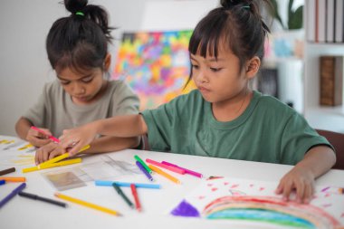 İki genç kız kalemler ve boyama kitaplarıyla bir masada oturuyorlar. Gülümsüyorlar ve eğleniyor gibi görünüyorlar. Kızlar çizim yaparken oyunculuk ve yaratıcılık kavramı