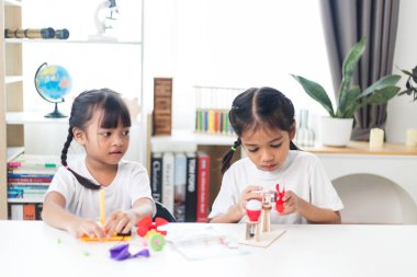 İki kardeş Asyalı kız evde yel değirmeni yığını oynuyorlar.