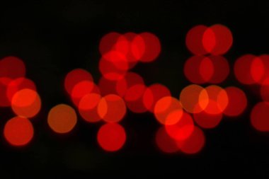 Gece karanlığında karanlığa bürünmüş renkli kırmızı bokeh noel ışıklarının soyut arkaplanı