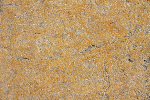 Grunge yellow orange brown old painted concrete or stone wall background texture with stains of faded paint peel and scaling, uneven and weathered