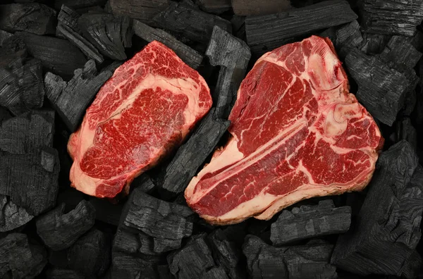 将一只年迈的优质大理石生牛肉片和牛排馆T骨牛排放在黑色炭块上 准备烧烤 高高在上 立正上方 — 图库照片