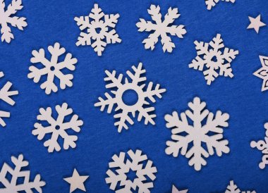Beyaz ahşap kar tanelerinin yakın desenleri mavi keçeli arka plan üzerine Noel süslemeleri, masa üstü manzarası, düz yatış