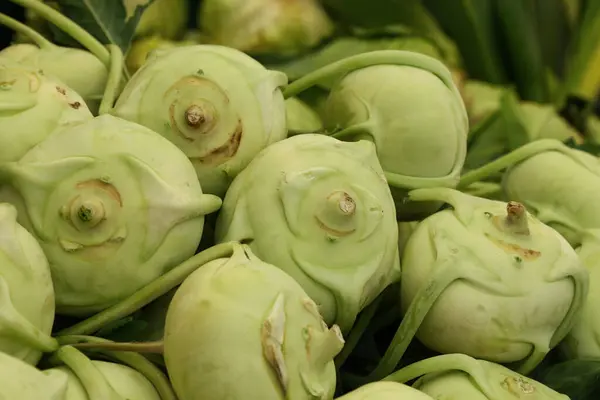 Close up fresh green kale turnip kohlrabi root cabbage at retail display of farmer market, high angle view