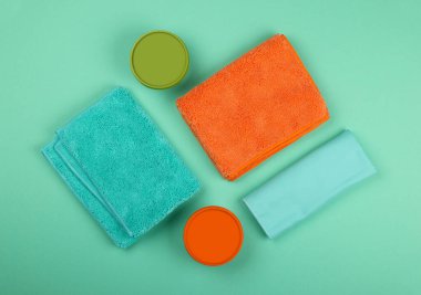 Birkaç yeni yumuşak renkli mikrofiber elbise, süngerler, paspaslar ve ev temizlik ürünleri, yüksek açı, düz yatak, masa üstü manzarası, tam üstte, kapat.