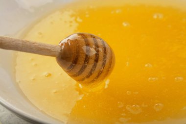 Bir ahşap bal kaşığını bir kase taze sıvı akasya ile kapat tatlım, yüksek açılı görüş.
