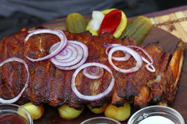 Izgara domuz pirzolası, soğan halkaları, biber ve soslar, yakın çekim, yüksek açı manzaralı.