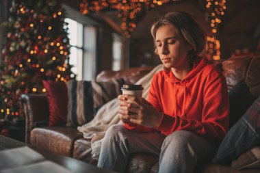 Uzun saçlı, düşünceli üzgün bakışlı, sinirli ve evde ağlayan genç bir çocuk. Şık bir zoomer olan Z jenerasyonu, yeni yıl tatilinde Noel ağacı ışıklarıyla süslenmiş 25 Aralık arifesi.