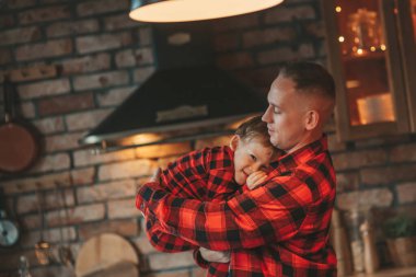 Kırmızı kareli elbiseli, Noel Baba 'yı evde bekleyen küçük oğlu olan aktif ailelere gülümseyin. Tarz sahibi aile, gülüşlere, kucaklaşmalara evde sarılmaya bayılır. 25 Aralık Noel Ağacı 'nın yeni yıl çelenkleri ve ışıkları kutlanır