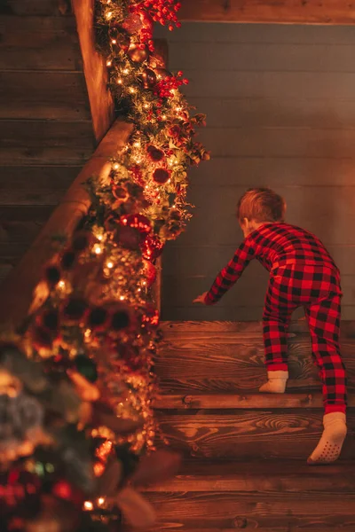 動く楽しさと奇跡のサンタを待っている笑顔の小さな子供がアクティブになっています 赤いチェッカースリーブ子供遊び楽しい室内ジャンプ移動笑うガーランドライトノエルツリーEve 12月 — ストック写真