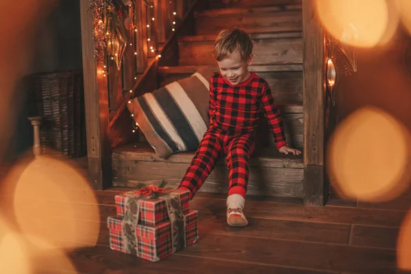奇跡のサンタオープンプレゼントを待っている楽しい時間を過ごしている笑顔の小さな子供 赤いチェッカードスリーズウェア陽気な子供お祝い新年でギフトボックスガーランドライトノエルでEve 12月 — ストック写真