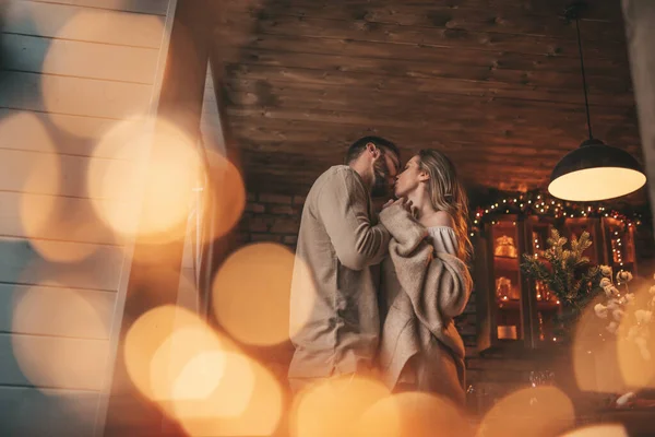 12月25日晚上 一对年轻貌美的情侣拥抱室内的肖像 情侣们笑着拥抱亲吻着在家中等待圣诞节的到来 用优雅的针织服装和柔情来庆祝新年 — 图库照片