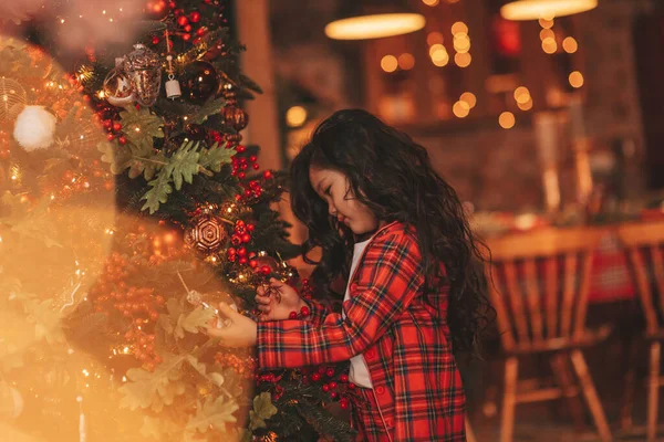サンタのポーズから奇跡を待っている幸せなかわいい日本の女の子の夢は 木を飾る アジアの子供黒巻き毛で赤い遊び服でお正月を祝うBokeh XmasライトEve 12月 — ストック写真