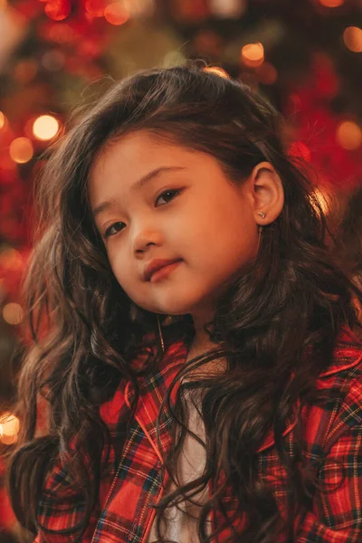 幸せな日本の女の子の夢を離れてサンタから奇跡を待っている木の近くにポーズをとっている アジアの子供黒巻き毛で赤い遊び服でお正月を祝うBokeh XmasライトEve 12月 — ストック写真