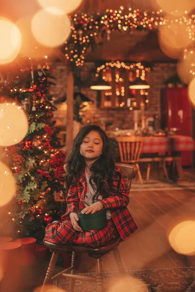 ノエルの木の近くの床にポーズをとっているサンタから奇跡を待っている幸せな日本の女の子の夢 アジアの子供で赤い遊び服お正月を祝うギフトボックスでBoque XmasライトEve 12月 — ストック写真
