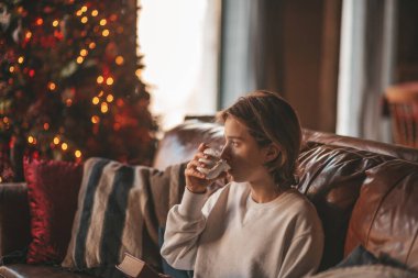 Uzun saçlı, düşünceli üzgün bakışlı, sinirli ve evde ağlayan genç bir çocuk. Şık bir zoomer olan Z jenerasyonu, yeni yıl tatilinde Noel ağacı ışıklarıyla süslenmiş 25 Aralık arifesi.