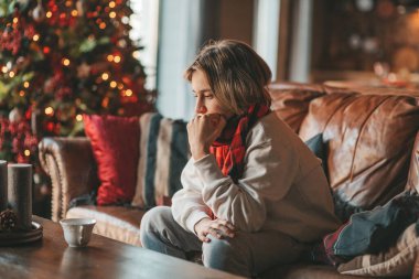 Uzun saçlı, düşünceli üzgün bakışlı, sinirli ve evde ağlayan genç bir çocuk. Şık bir zoomer olan Z jenerasyonu, yeni yıl tatilinde Noel ağacı ışıklarıyla süslenmiş 25 Aralık arifesi.