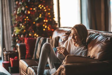 Genç, duygusal, neşeli, uzun saçlı, kahkahalar atan ve rahat evinde neşeli bir çocuk. Zoomer Z jeneratörünün keyfi yerinde. 25 Aralık arifesi Noel arifesi Noel ağacıyla Noel tatili kutlanıyor.