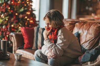 Genç, duygusal, neşeli, uzun saçlı, kahkahalar atan ve rahat evinde neşeli bir çocuk. Zoomer Z jeneratörünün keyfi yerinde. 25 Aralık arifesi Noel arifesi Noel ağacıyla Noel tatili kutlanıyor.