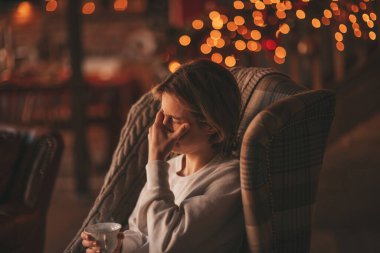 Uzun saçlı, düşünceli üzgün bakışlı, sinirli ve evde ağlayan genç bir çocuk. Şık bir zoomer olan Z jenerasyonu, yeni yıl tatilinde Noel ağacı ışıklarıyla süslenmiş 25 Aralık arifesi.