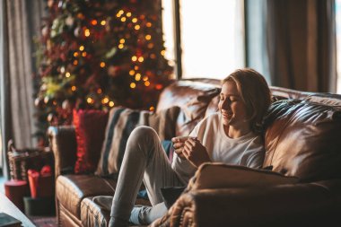 Genç, duygusal, neşeli, uzun saçlı, kahkahalar atan ve rahat evinde neşeli bir çocuk. Zoomer Z jeneratörünün keyfi yerinde. 25 Aralık arifesi Noel arifesi Noel ağacıyla Noel tatili kutlanıyor.