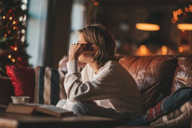 Uzun saçlı, düşünceli üzgün bakışlı, sinirli ve evde ağlayan genç bir çocuk. Şık bir zoomer olan Z jenerasyonu, yeni yıl tatilinde Noel ağacı ışıklarıyla süslenmiş 25 Aralık arifesi.