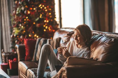 Genç, duygusal, neşeli, uzun saçlı, kahkahalar atan ve rahat evinde neşeli bir çocuk. Zoomer Z jeneratörünün keyfi yerinde. 25 Aralık arifesi Noel arifesi Noel ağacıyla Noel tatili kutlanıyor.