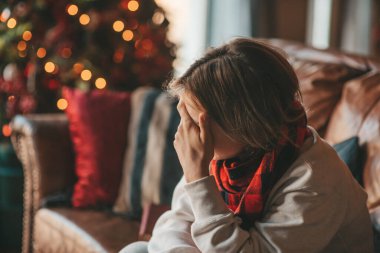 Uzun saçlı, düşünceli üzgün bakışlı, sinirli ve evde ağlayan genç bir çocuk. Şık bir zoomer olan Z jenerasyonu, yeni yıl tatilinde Noel ağacı ışıklarıyla süslenmiş 25 Aralık arifesi.