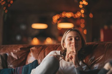 Genç, duygusal, neşeli, uzun saçlı, kahkahalar atan ve rahat evinde neşeli bir çocuk. Zoomer Z jeneratörünün keyfi yerinde. 25 Aralık arifesi Noel arifesi Noel ağacıyla Noel tatili kutlanıyor.