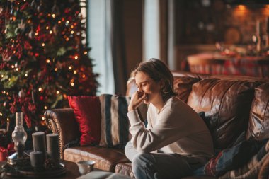 Genç, duygusal, neşeli, uzun saçlı, kahkahalar atan ve rahat evinde neşeli bir çocuk. Zoomer Z jeneratörünün keyfi yerinde. 25 Aralık arifesi Noel arifesi Noel ağacıyla Noel tatili kutlanıyor.